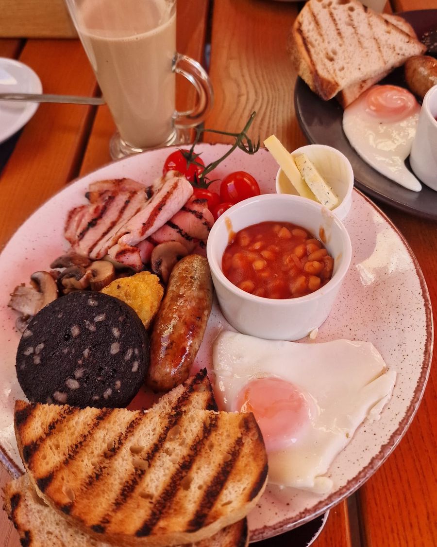 A full breakfast plate with toast, eggs and a latte