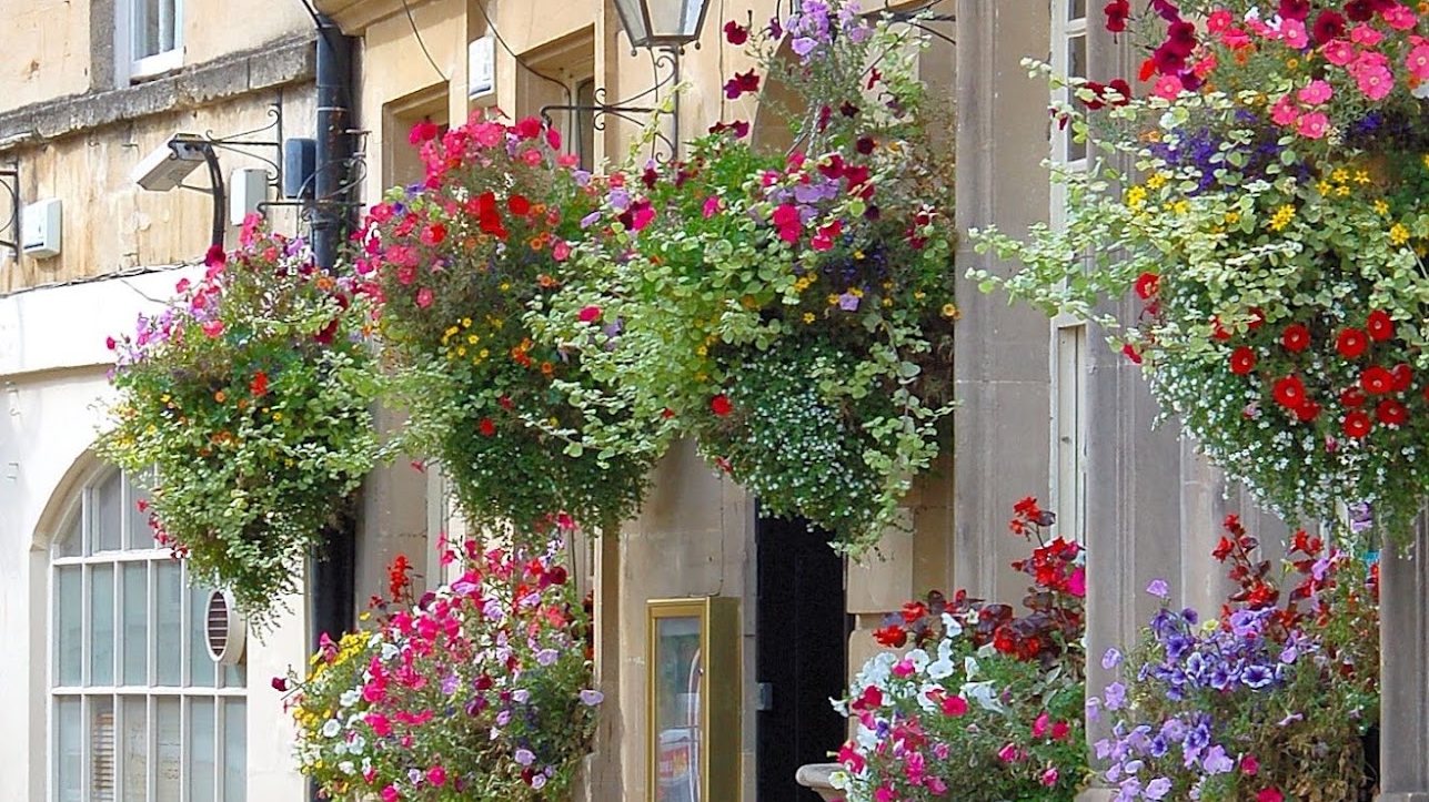 The flower-hung Georgian facade and terrace tables of Garrick's Head on St John's Place, Bath