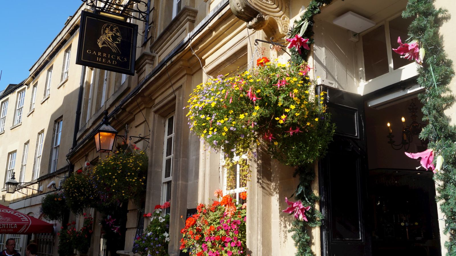 Garrick's Head sign and hanging baskets on the street leading to the Theatre Royal, Bath